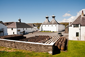 A photo of the Ardbeg Whiskey Distillery with barrels in front of the building